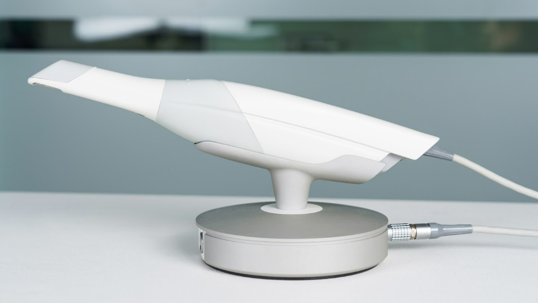 Intraoral scanner handpiece resting on its round docking station.